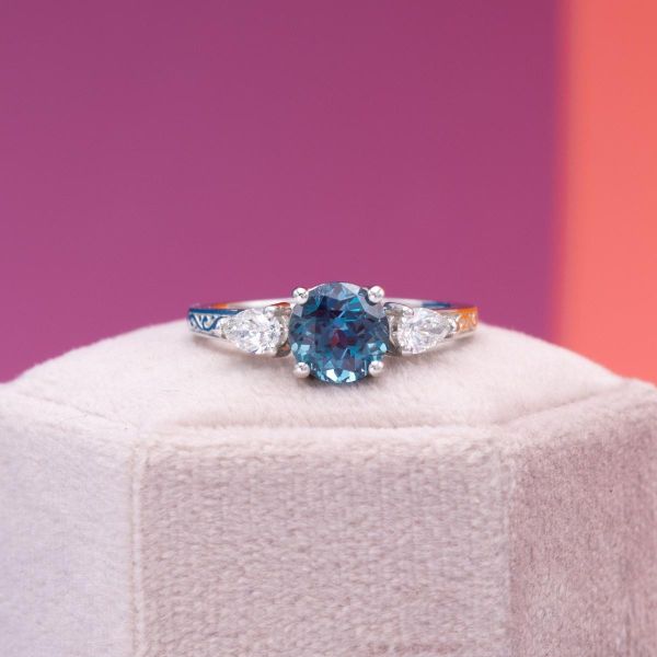 This round brilliant alexandrite sits in the center of pear diamond accents and a white gold band.