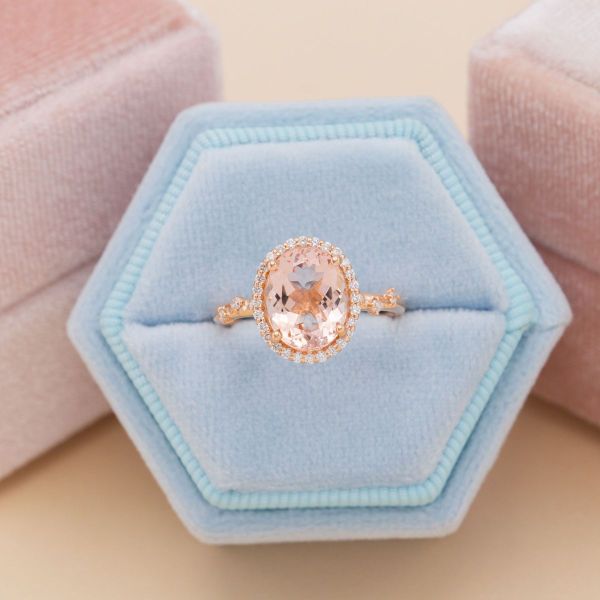A large peach colored, oval cut morganite in a diamond halo.