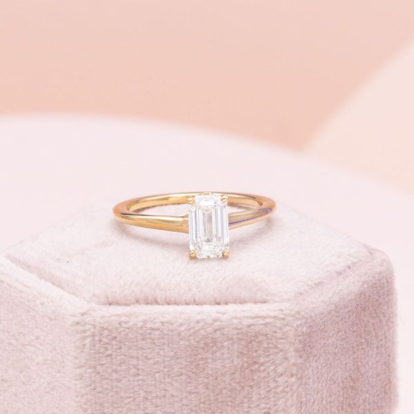 A cathedral setting pairs nicely with a trellis setting to add interest to the side profile of this emerald cut engagement ring.
