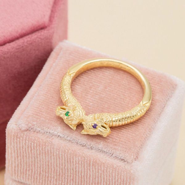 This yellow gold engagement ring features two stately dragons with eyes of emerald and amethyst.