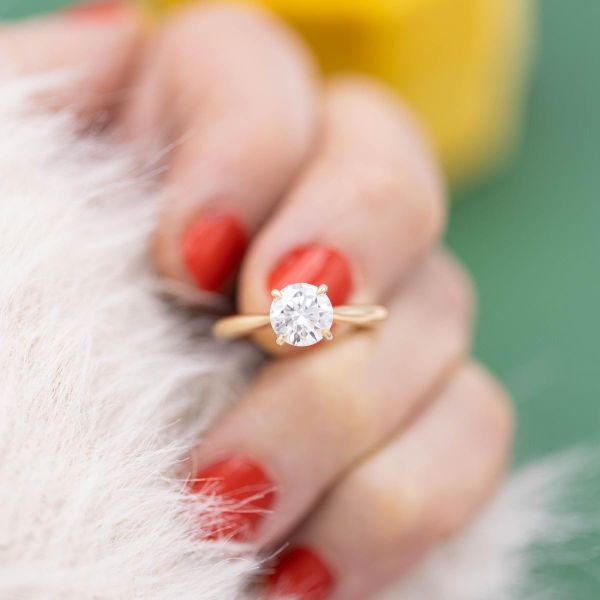A brilliant round lab created diamond shines brightly in a yellow gold solitaire engagement ring.