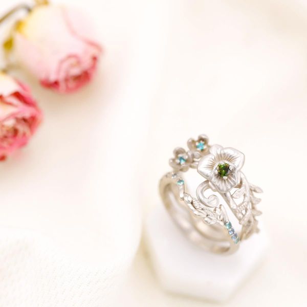 A detailed orchid flower engagement ring with green tourmaline, alexandrite and aquamarine accents.