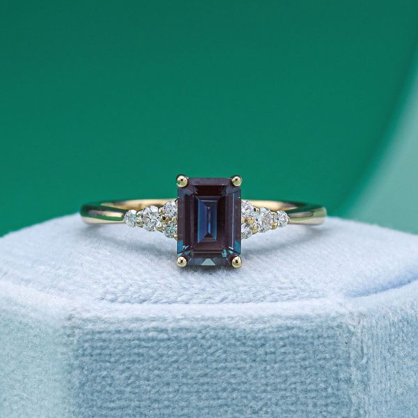 This deep blue alexandrite engagement ring holds diamond accents in a yellow gold band.
