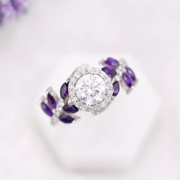 This halo diamond ring features diamond and marquise shaped amethyst accents on a white gold band.