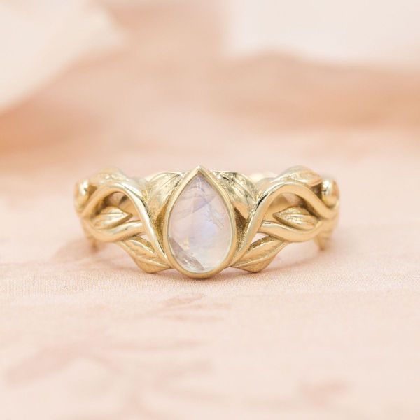 Elven inspiration runs wild in this his and hers bridal set and wedding band, featuring intertwining yellow gold metalwork and teardrop shaped moonstones.
