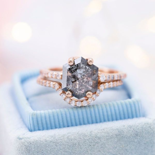 A hexagon cut salt and pepper diamond makes the center stone of this rose gold engagement ring.