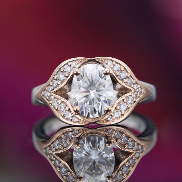 白色和玫瑰金订婚戒指与优雅的弯曲劈柄周围椭圆形莫桑石中心石。