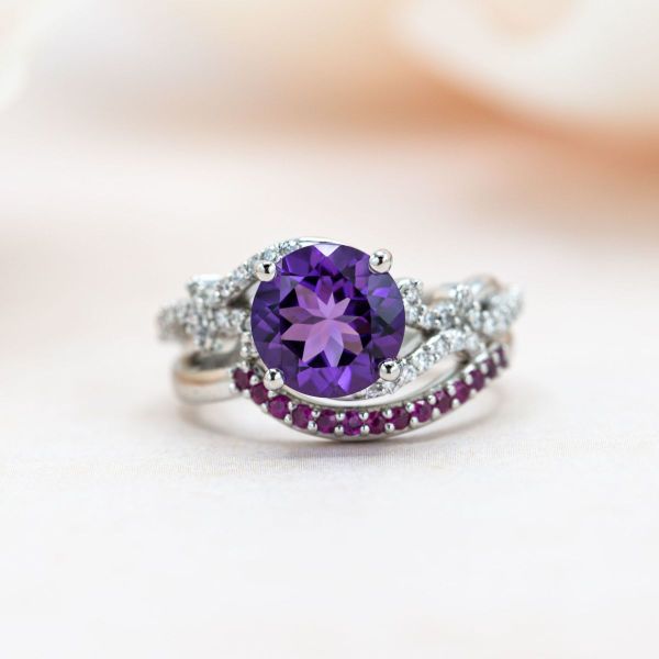 An amethyst center stone is accented with diamonds and rubies on this bridal set.