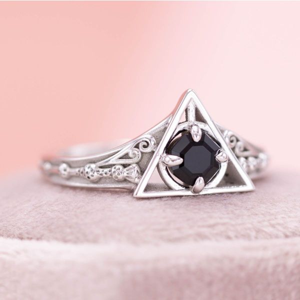 An octagonal black onyx centers this engagement ring with Deathly Hallows and Elder Wand inspired detailing, giving it an ominous feel.