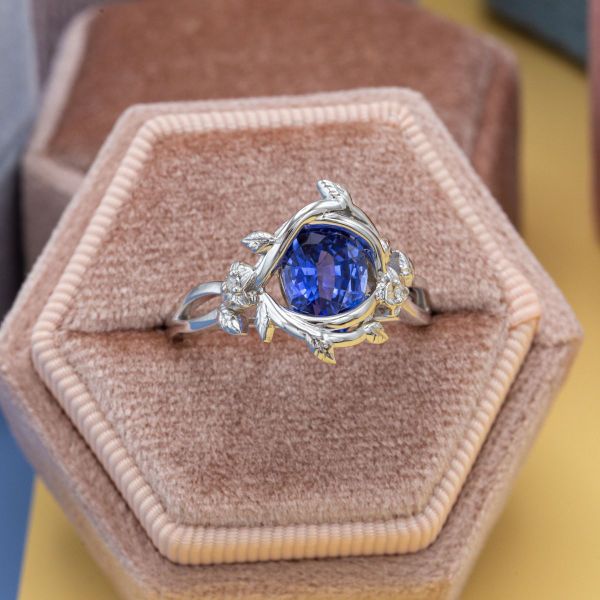 White gold leafy vines literally grow across the center stone in this ring but not even a creeping vine can dampen the brilliance of this light blue lab-created sapphire. We added touches of sparkle with dew drop diamonds scattered among the leaves.
