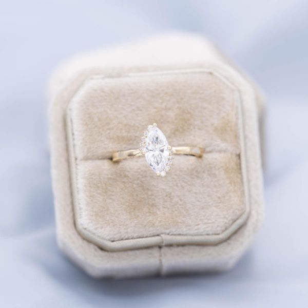 A semi-halo of offset, graduated diamonds frames this ring's marquise cut diamond center stone.