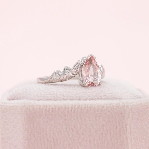 The pear shaped morganite melts into the white gold mountains making up the band.
