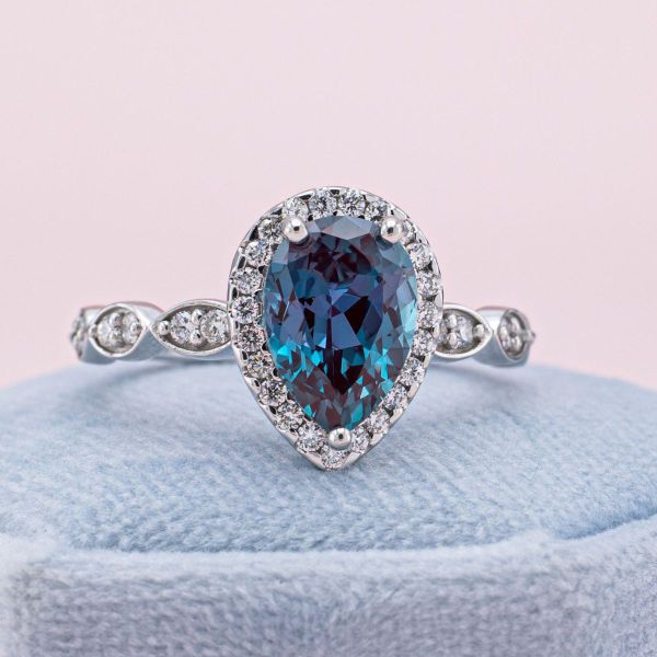A pear cut, lab created alexandrite centers this white gold engagement ring.