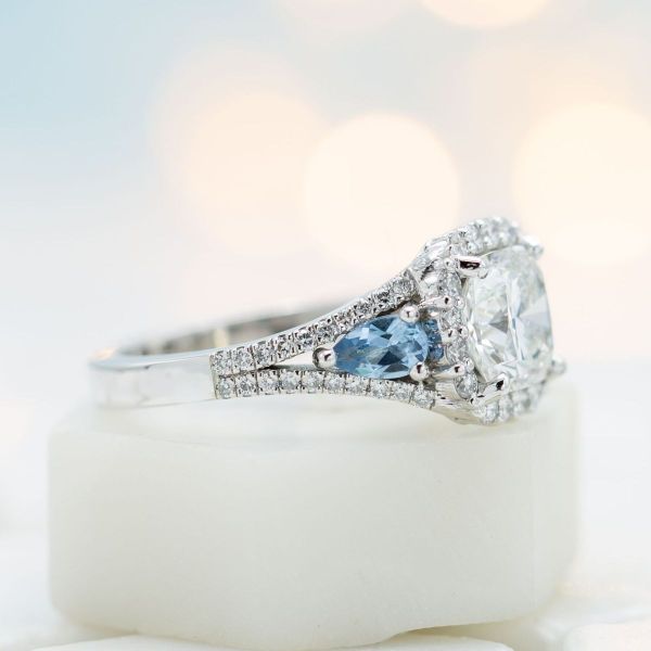 Aquamarine and garnet accents add color to this cushion cut diamond halo engagement ring.