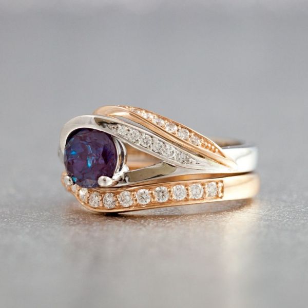 A ring of contrasts. The center stone is set with a half-bezel and two prongs, and curves of rose and white gold stretch over each other in contrast to the minimalism on the other side of the center stone.