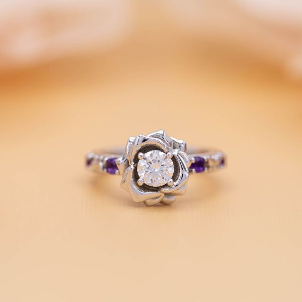Butterflies play amongst amethyst accents around a lab-created diamond in this butterfly inspired engagement ring.