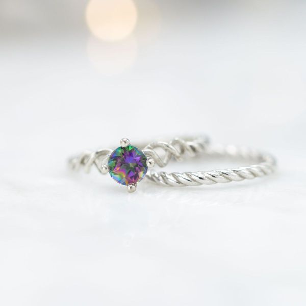 A mystic topaz sits at the heart of this cable braided white gold bridal set with a sentimental date engraved near the base of the engagement ring.