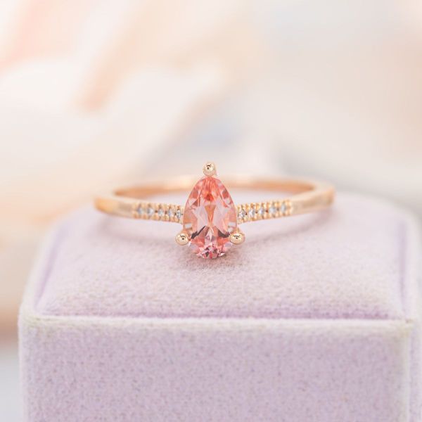 This bridal set features a solitaire, pear cut sapphire in light pink that feels warm against a rose gold band, with a matching tiara wedding band.