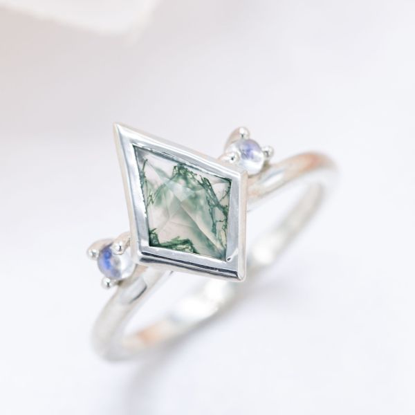 Three-stone engagement ring with kite cut moss agate and moonstones.