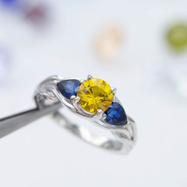 深黄色和蓝色的蓝宝石在这枚三石订婚戒指上形成了鲜明的对比。
