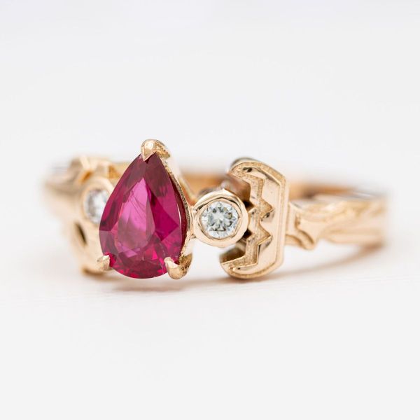 Connected at their hilts, this Sword Art Online inspired anime engagement ring features a pear cut ruby.