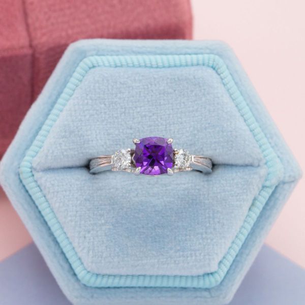 A cushion cut amethyst sits in the center of the white gold engagement ring with diamond accents.