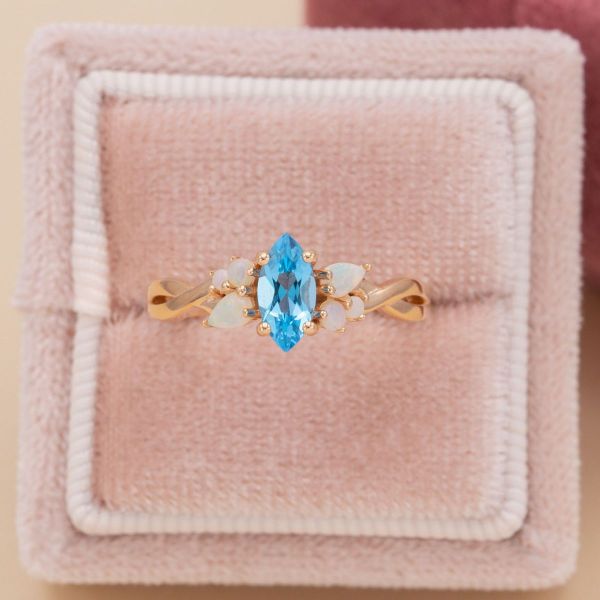 A Swiss blue topaz is surrounded by white opals in this winter inspired engagement ring.