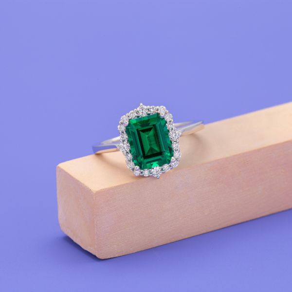 This emerald is set on a white gold band with an antique frame style halo.