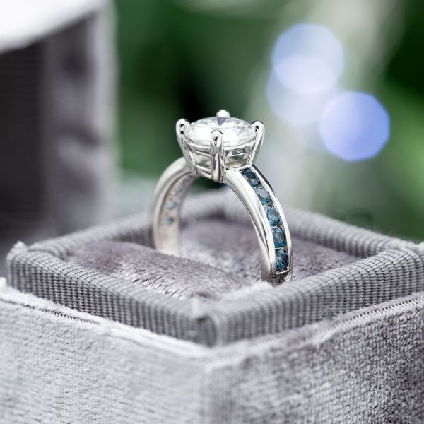 现代白金戒指与通道设置翠绿宝石强调中心钻石。