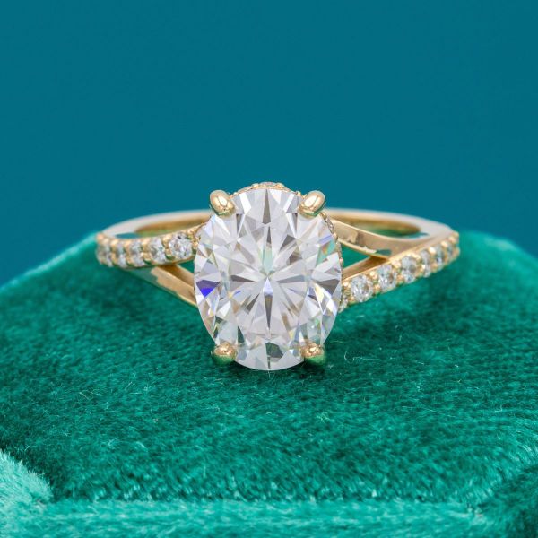 The shape of the oval moissanite center stone is accentuated by the split-shank setting in this engagement ring.