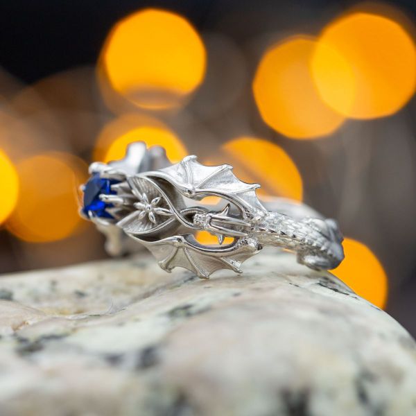 Fine craftsmanship is on full display in this engagement ring with two full-length dragons bowing to a deep blue center gemstone.