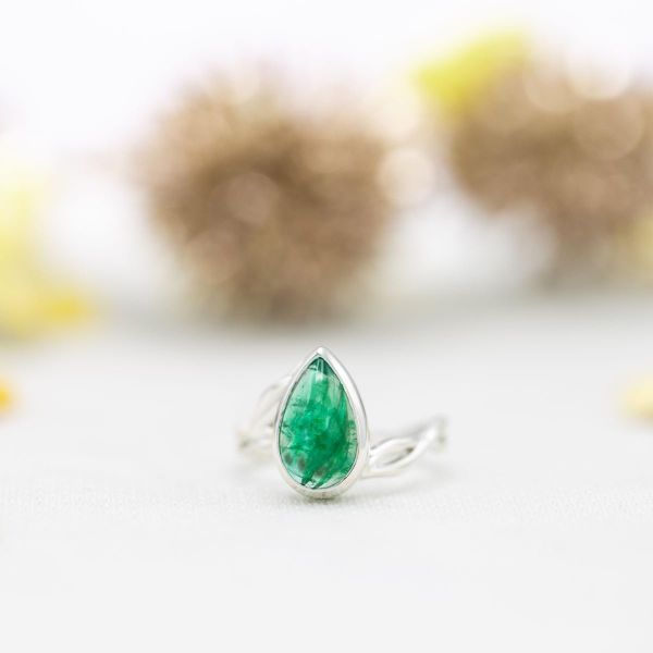 这枚订婚戒指采用了一颗cababochon切割的祖母绿，看起来与众不同。
