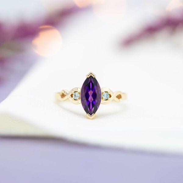 This marquise cut amethyst is held by yellow gold V-prongs and flanked by diamond accents.