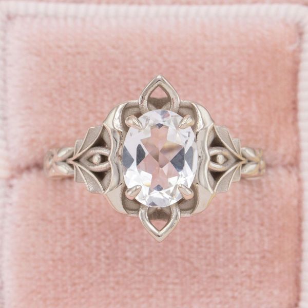 A princess-inspired setting, this intricate white gold ring holds a clear white topaz.
