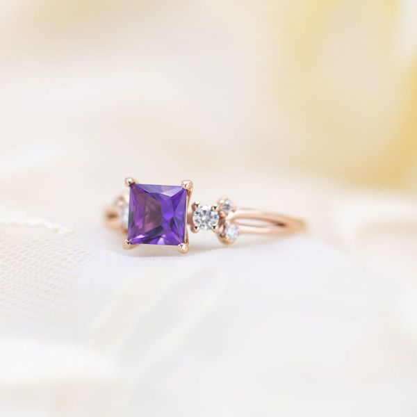 This princess cut amethyst is held in rose gold with an array of diamond side stone accents.