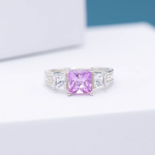 A pink sapphire engagement ring with diamond accents and white gold.