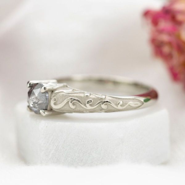 This otherworldly engagement ring features a rose cut salt and pepper diamond at its center, with a white gold band.