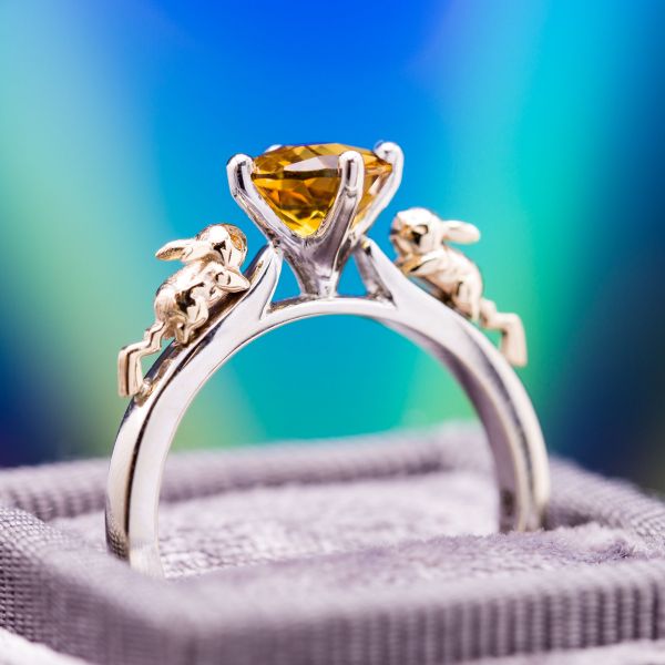 A Pokemon fan's wonderfully whimsical concept features yellow gold Pikachus dashing up the white gold engagement ring shank toward a bright orange citrine center stone.