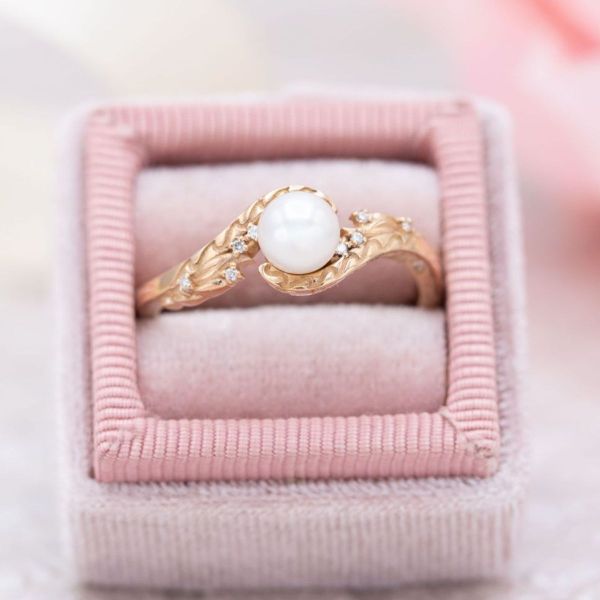 A sophisticated yellow gold ring with a delicate white pearl fresh out of the ocean in this mermaid engagement ring