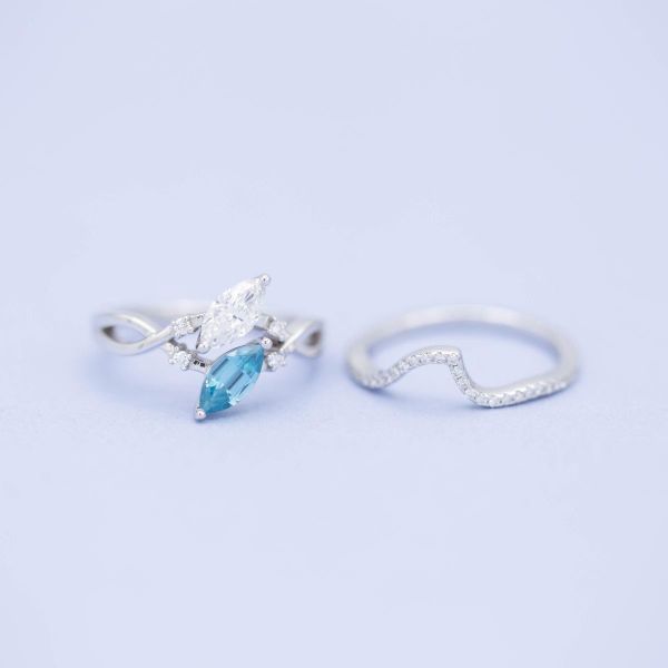 Ocean wave-inspired engagement ring with a two stone arrangement of marquise cut diamond and blue zircon.