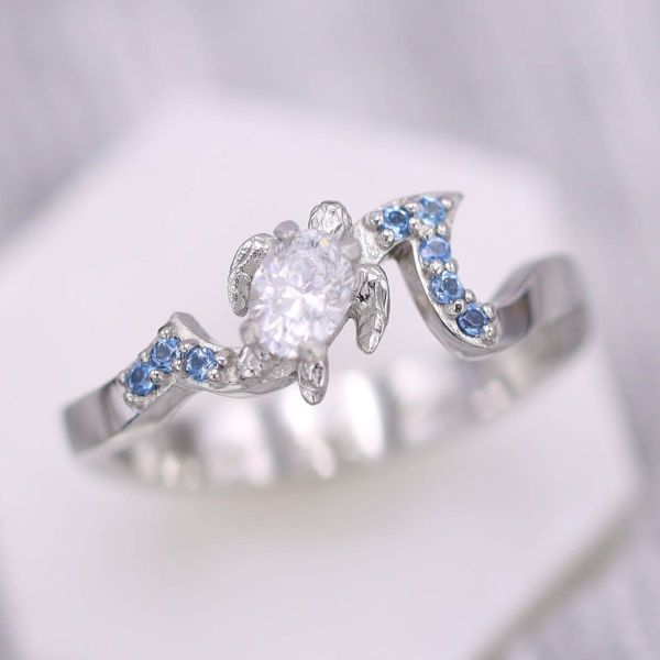 A turtle made of diamonds with aquamarine accents brings the ocean engagement ring to life.