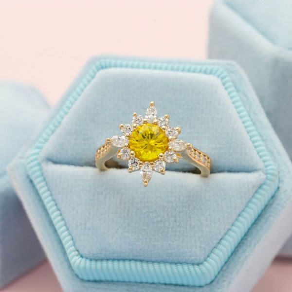Yellow sapphire engagement ring with a sunburst halo and yellow gold band.