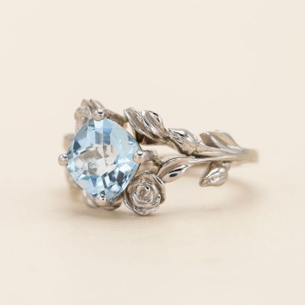 White gold roses grow around a sky blue topaz in our first rose engagement ring.