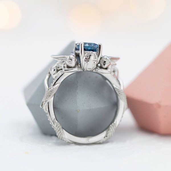 An oval London blue topaz sits between moissanite accents in this white gold setting.
