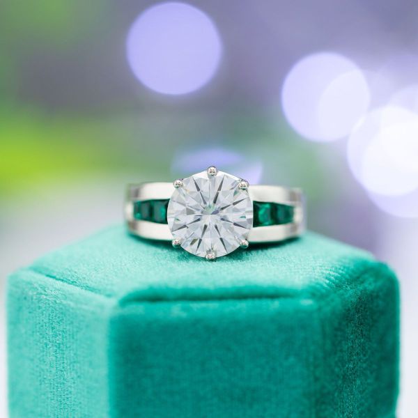 This moissanite ring with emerald accents features engravings that commemorate the couple’s first trip to Hawaii and Nightmare Before Christmas-inspired icons Jack and Sally.
