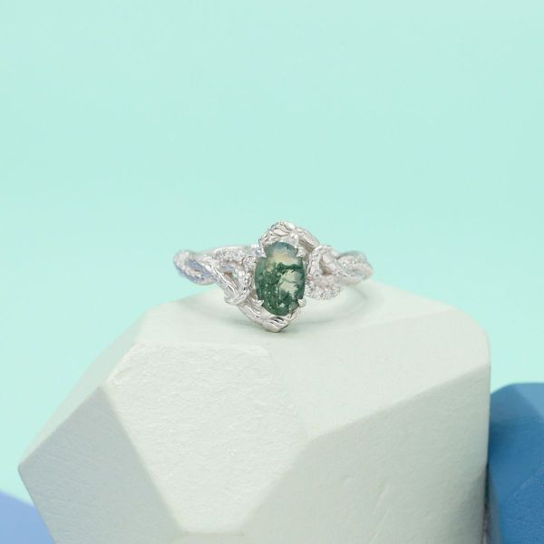 An oval moss agate engagement ring in white gold.