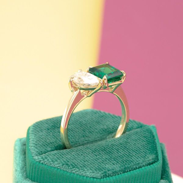 An emerald and diamond share the spotlight on this yellow gold band.