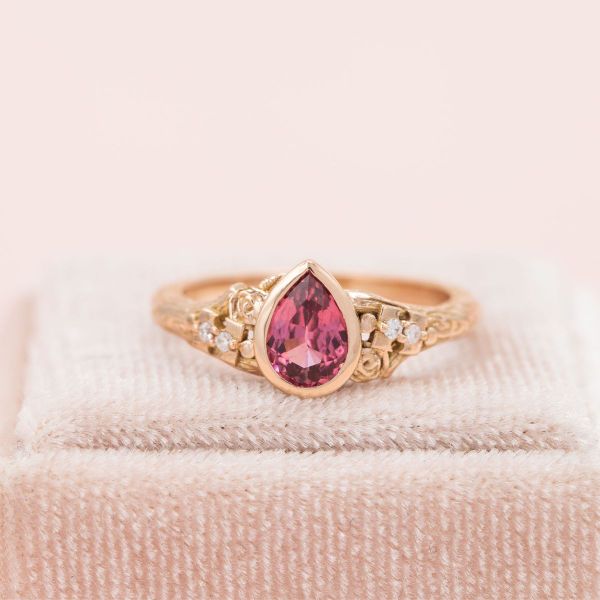 A pink spinel center stone in yellow gold bezel setting.