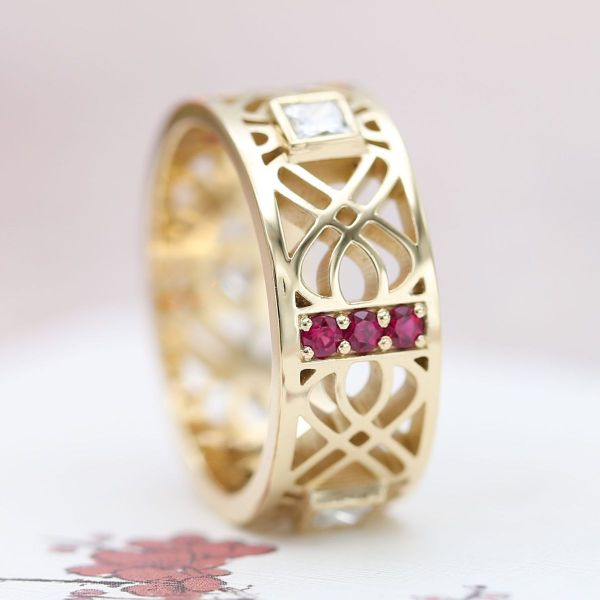 Angular edges are softened by flowing lines as well as diamond and ruby accents in this yellow gold men’s engagement ring.