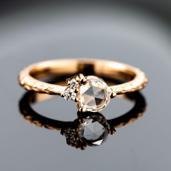 A rose cut center diamond, an antique cut, is paired with two modern round brilliant cut accents set like orbiting moons at a slight angle to create a unique cluster arrangement.